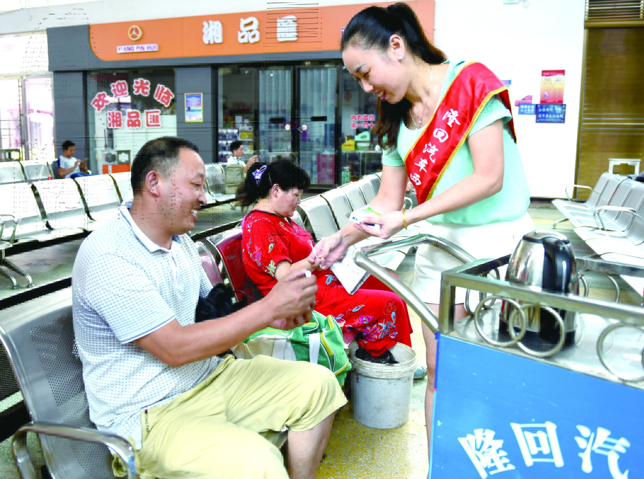 隆回分公司汽車西站工作人員正在為旅客免費(fèi)贈(zèng)送藿香正氣水。